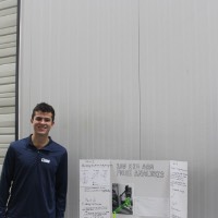 Two students standing next to a trifold presentation.
